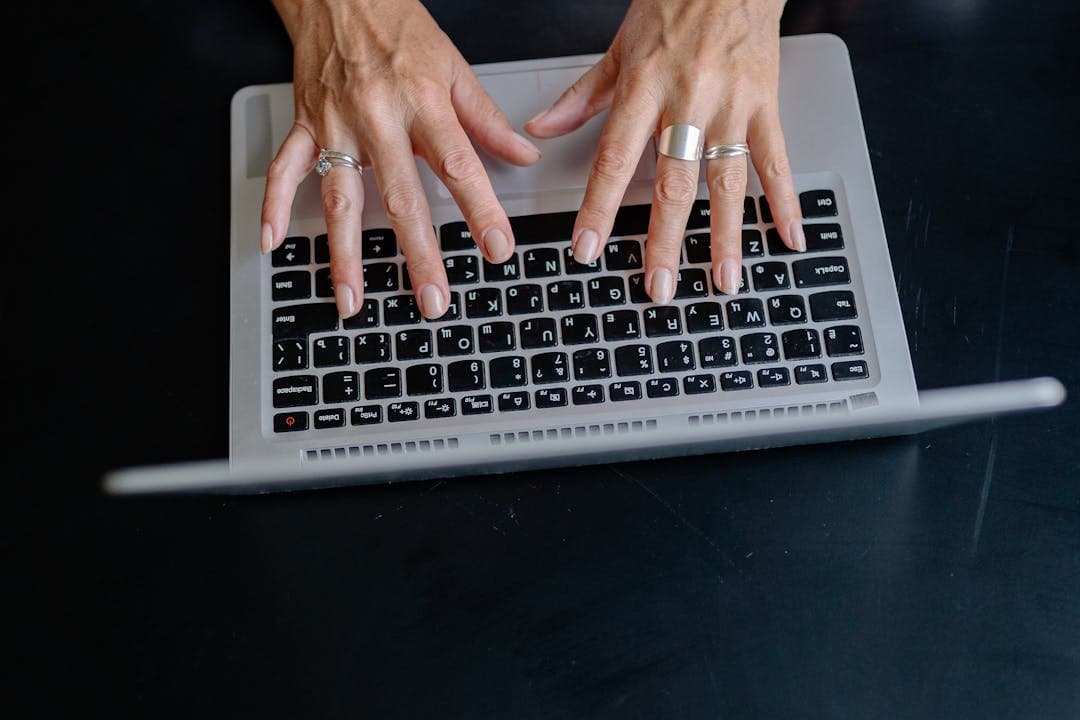 블랙 배경 위에서 키보드를 타이핑하는 여성의 손 클로즈업