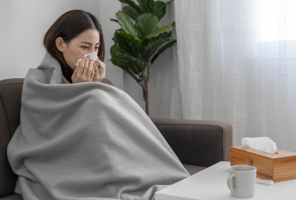 이불을 덮고 코를 풀고있는 여성