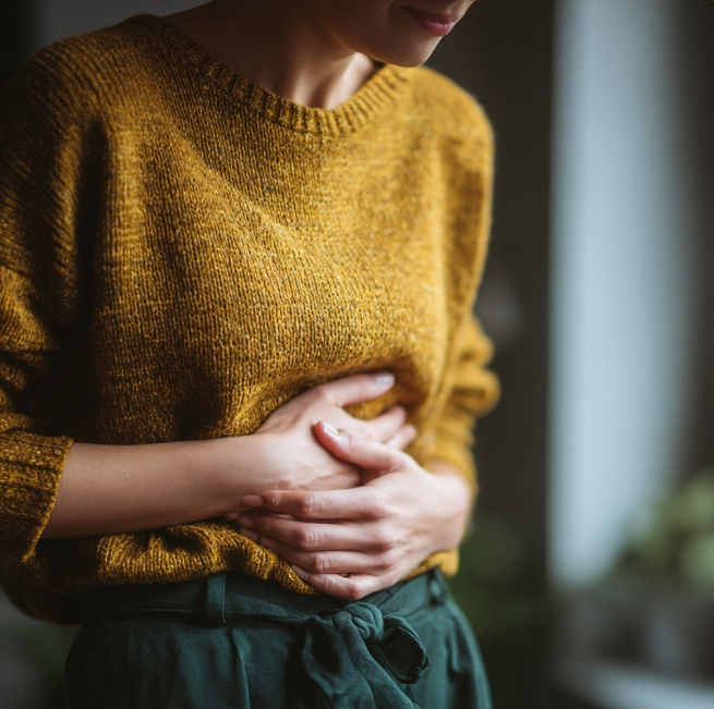 속이 쓰려 배를 움켜잡은 여성