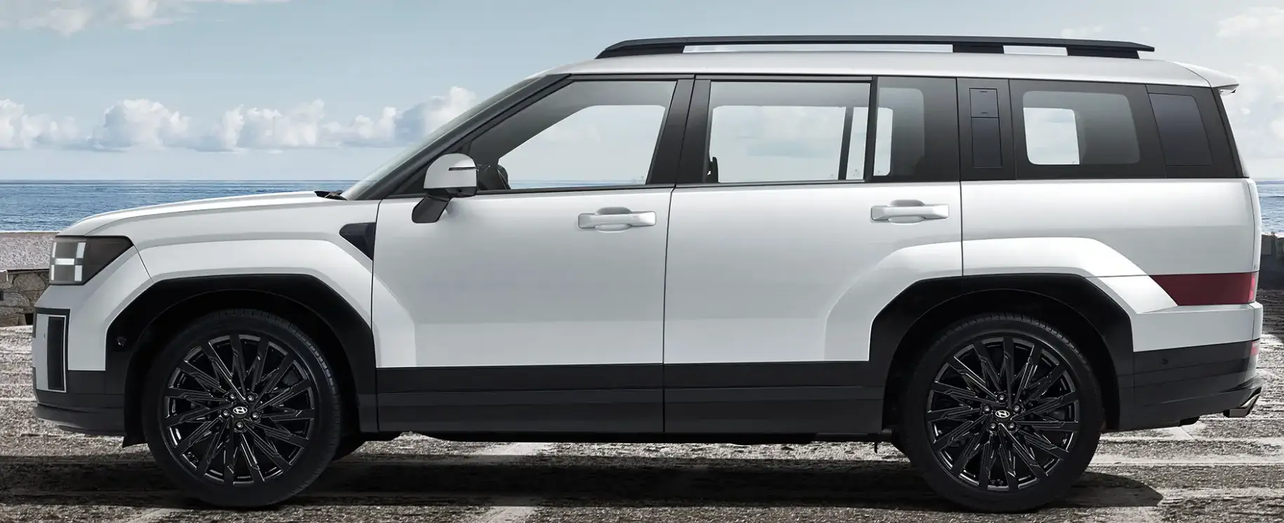 회색 시멘트 바닥 뒤 파란바다와 푸른하늘을 배경으로 서있는 흰색 싼타페 자동차