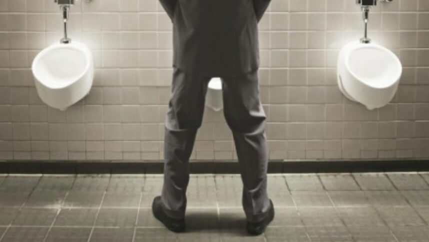 공중 화장실 소변기에 남성이 소변을 보고 있다